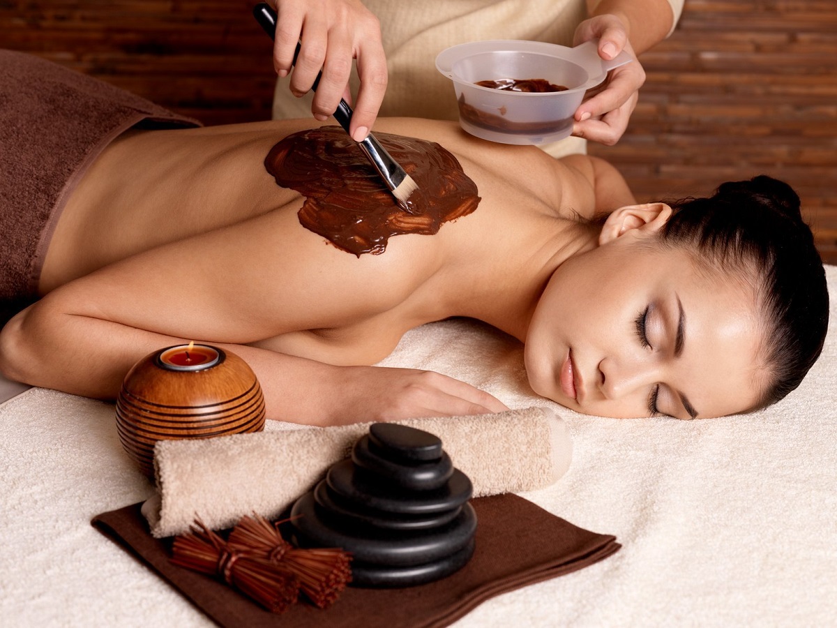 Spa therapy for young woman receiving cosmetic mask on back at beauty salon